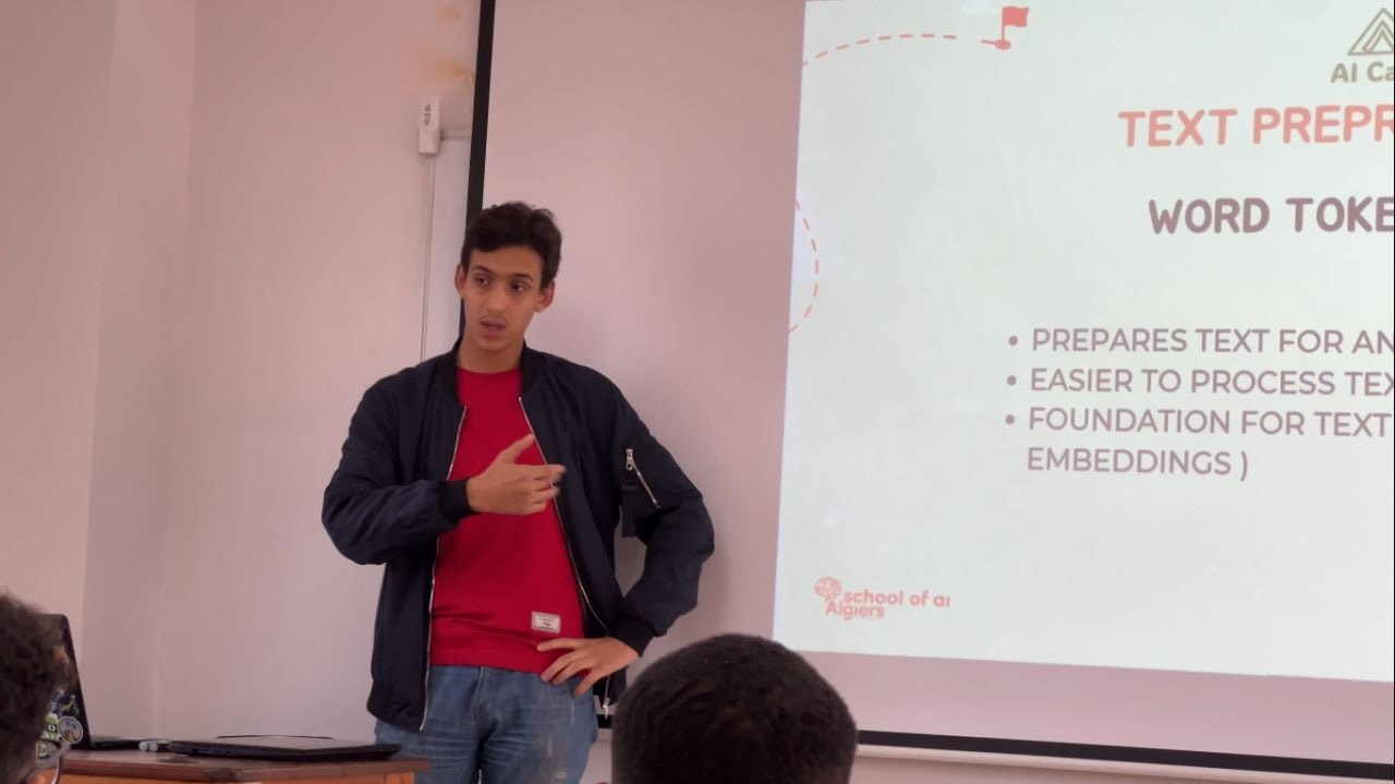 شامل نذير بوعشة يدرّس في AI Camp لـ School of AI Algiers، بجانب شريحة عن المعالجة المسبقة للنص وتقطيع الكلمات